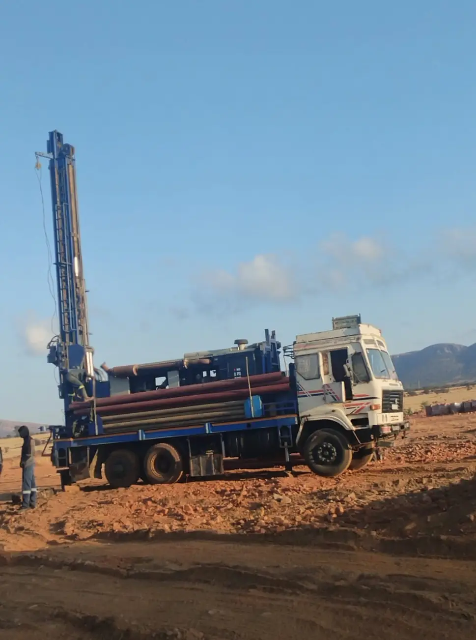 Borehole drilling rig and truck in a dirt field